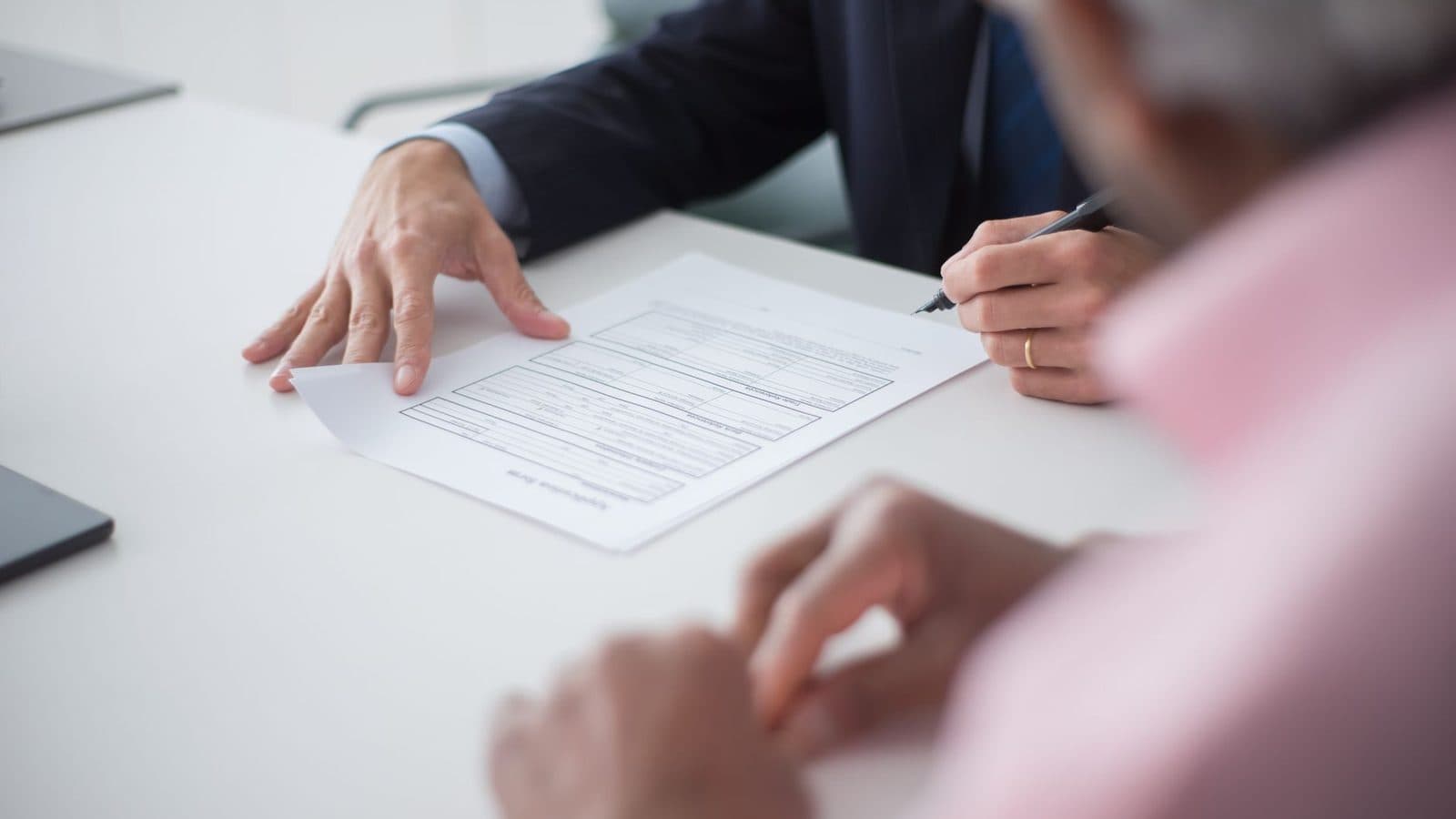 Duas pessoas revisando um documento impresso sobre a mesa de reunião