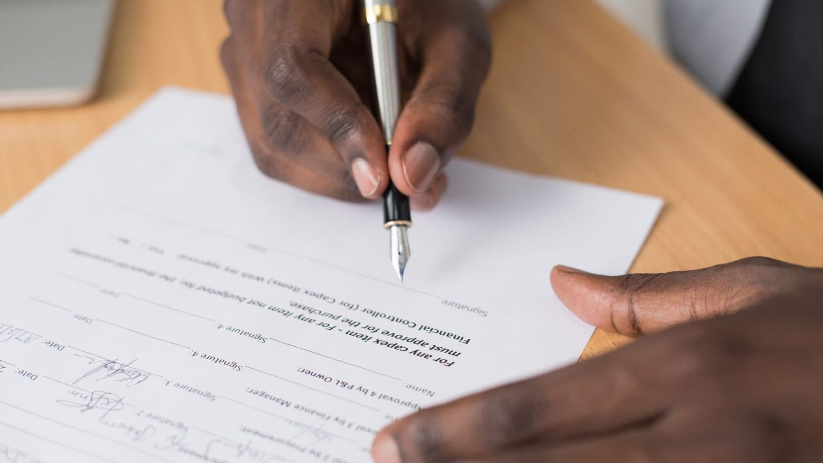 Pessoa redigindo um documento à mão sobre a mesa de trabalho