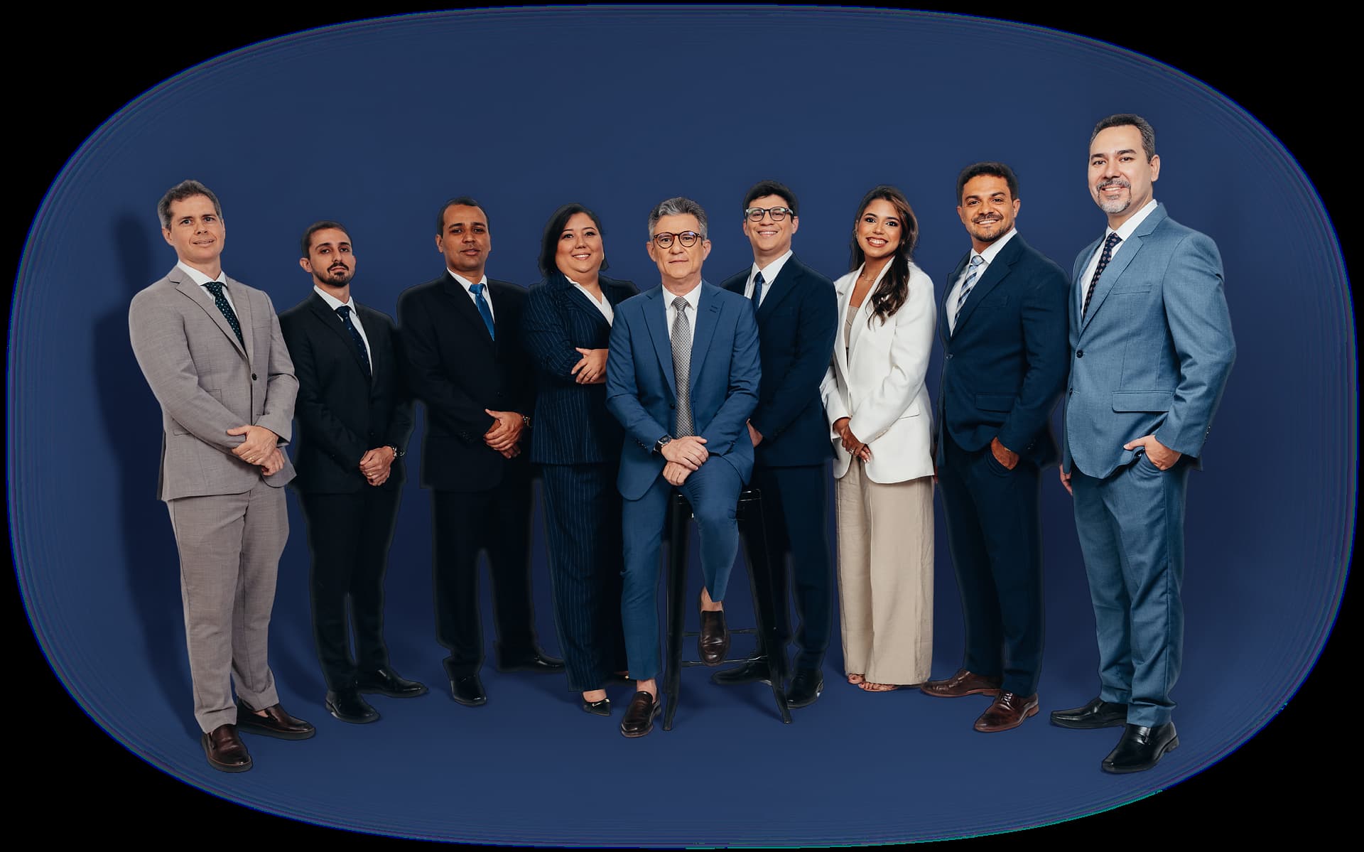 A equipe do Medeiros Buarque Advocacia & Consultoria reunida: nove profissionais em trajes formais, lado a lado, com o sócio fundador sentado ao centro.