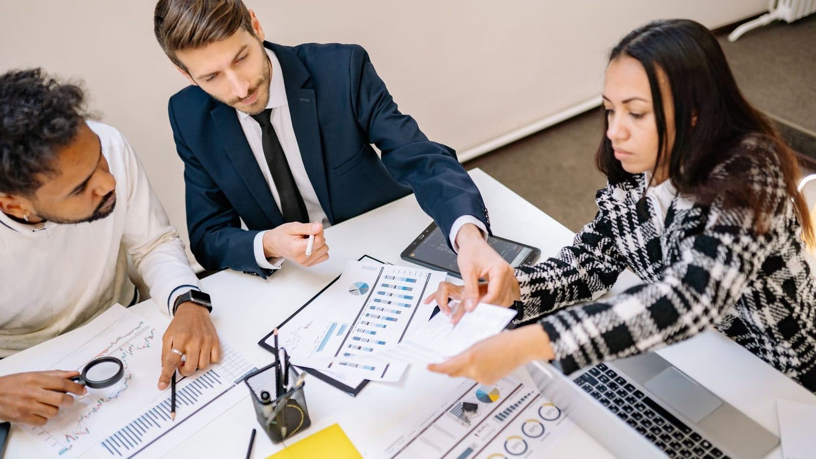 Equipe reunida analisando documentos e planilhas em mesa de trabalho